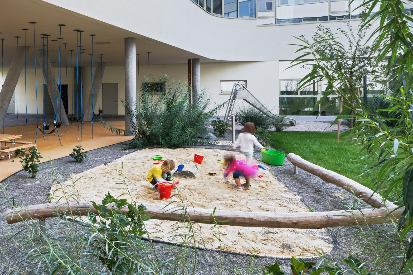 Kinder spielen auf einem Spielplatz im Innenhof eines Neubaus